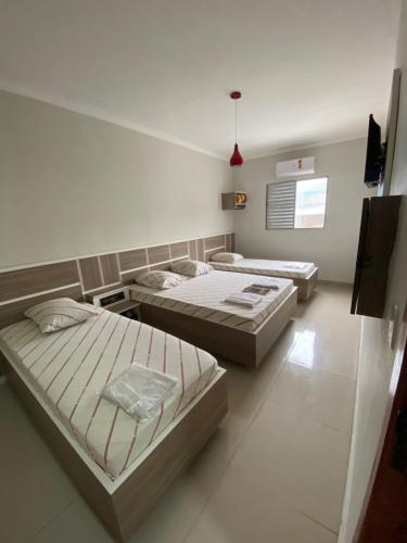 um quarto com três camas e uma tv nele em Hotel Cumbica em Guarulhos