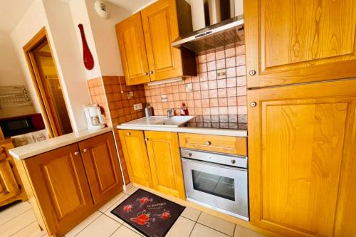 une cuisine avec des armoires en bois, un évier et une cuisinière dans l'établissement Nice 36 M2 With Wifi Balcon View On The Mountain, au Monêtier-les-Bains