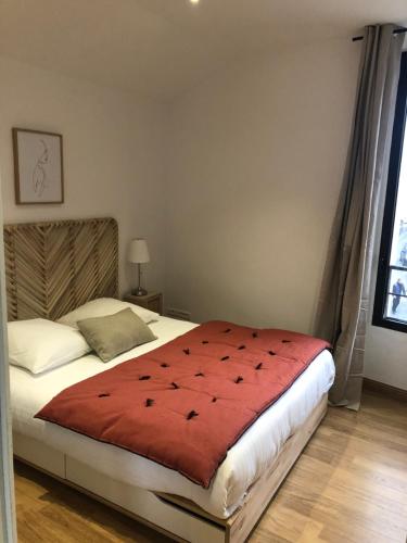 a bedroom with a bed with a red comforter at Entre les Arènes et la Major in Arles