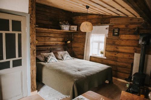 um quarto com uma cama num quarto com paredes de madeira em Vienkiemio Oazė - Namelis Prie Šermukšnio em Galvokai