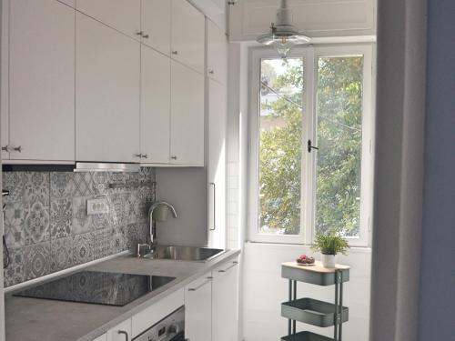a white kitchen with a sink and a window at Apartment Céleste - Directly on the Beach in Mošćenička Draga
