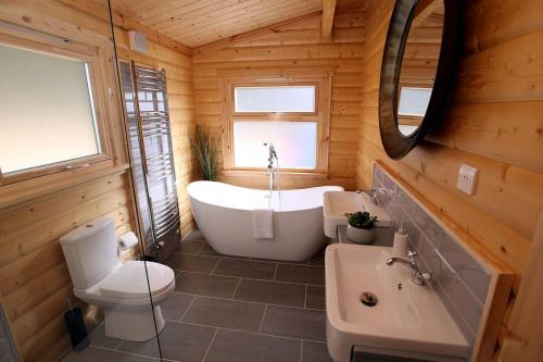 a bathroom with a tub and a toilet and a sink at Cambridgeshire Lakes - luxury lodges in a stunning lake location in Gamlingay