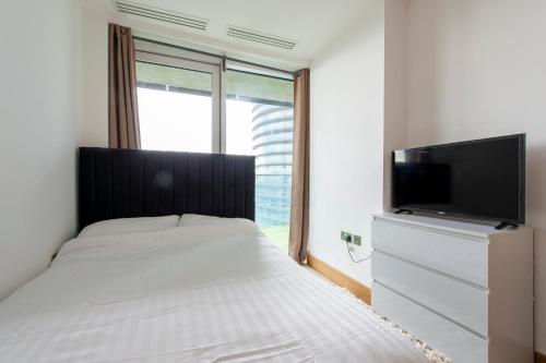 1 dormitorio con 1 cama y TV de pantalla plana en Canary Luxe Apartment, en Londres