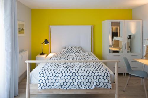 a bedroom with a white bed and a yellow wall at Exklusives Apartment inklusive Netflix und Parkplatz in Karlsruhe
