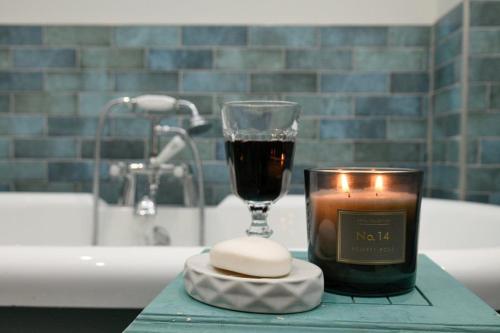 a candle and a glass of wine on a bathroom counter at Blackmount House in Oban