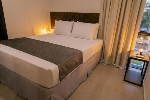 a bed in a hotel room with a window at TuCasa Flats - Viva uma experiência de morador! in Foz do Iguaçu