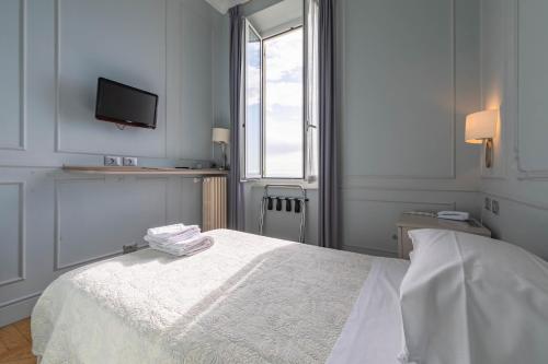 a white bedroom with a bed and a tv on the wall at Hotel Eden Alaxi Hotels in Alassio