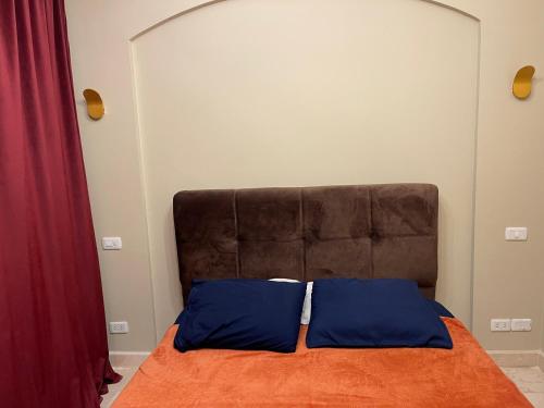 ein Bett mit einer orangefarbenen Decke und blauen Kissen in der Unterkunft El Gouna 1 Bedroom Apartment west golf ground floor in Hurghada