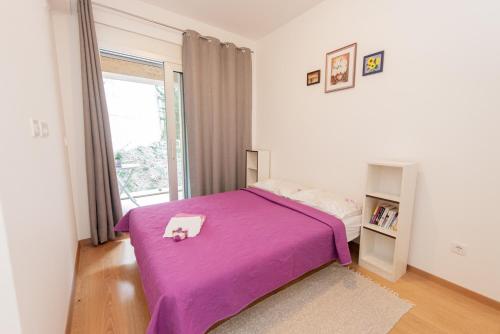 a bedroom with a purple bed and a window at Apartment Peace in Kotor