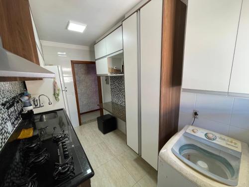 uma pequena cozinha com um lavatório e uma máquina de lavar roupa em Apartamento c/estacionamento, próximo ao Shopping em Vila Velha