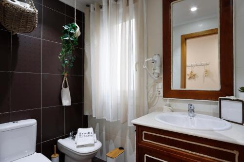 a bathroom with a sink and a toilet and a mirror at Apartamento Terraza vistas a la Ria y Parking in Ribadeo
