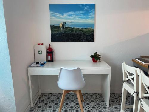 a white desk with a chair and a picture on the wall at Relaxing house by the beach - Casa Rosa in Horta
