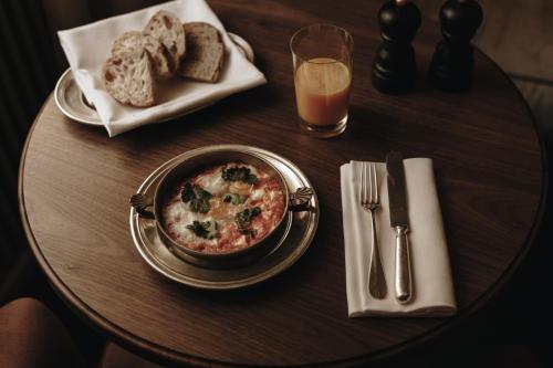 a table topped with a bowl of soup and bread at Parkhotel Mondschein, a Member of Design Hotels in Bolzano