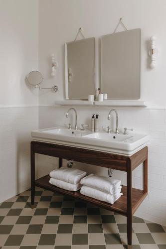 a bathroom with a sink and a mirror and towels at Parkhotel Mondschein, a Member of Design Hotels in Bolzano