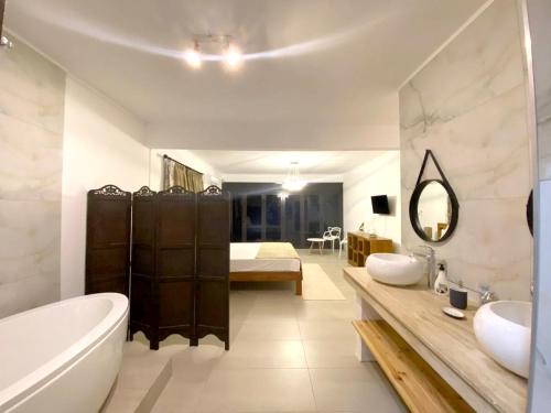a bathroom with a tub and a sink and a bed at Charming House with Mountain View - Trou d'Eau Douce in Trou dʼ Eau Douce