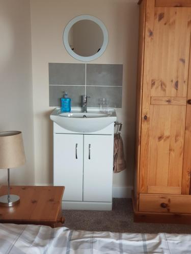 uma casa de banho com um lavatório branco e um espelho. em Southcote em Weston-super-Mare