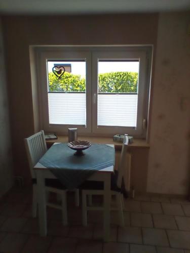 a table and chairs in a room with two windows at Ferienwohnung Fritz in Groß Vollstedt