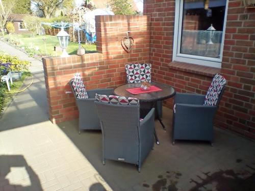 a patio with a table and chairs and a brick wall at Ferienwohnung Fritz in Groß Vollstedt