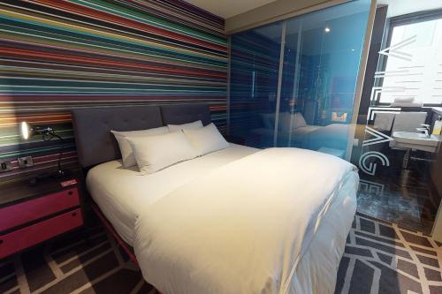 a bedroom with a large bed with a striped wall at Village Hotel Portsmouth in Portsmouth