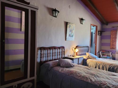a bedroom with two beds and a table with a lamp at Casa del Procurador in Las Virtudes