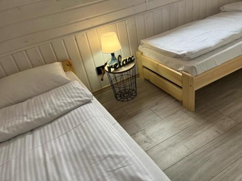 a bedroom with two beds and a lamp on a floor at Domkoland in Dziwnówek