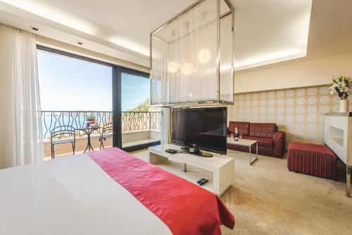 1 dormitorio con 1 cama grande y TV en Hotel & Apartments HEC Residence en Sveti Stefan