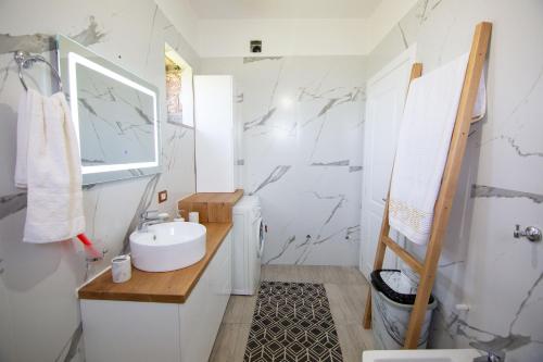 a white bathroom with a sink and a mirror at Villa Kadiu in Korçë