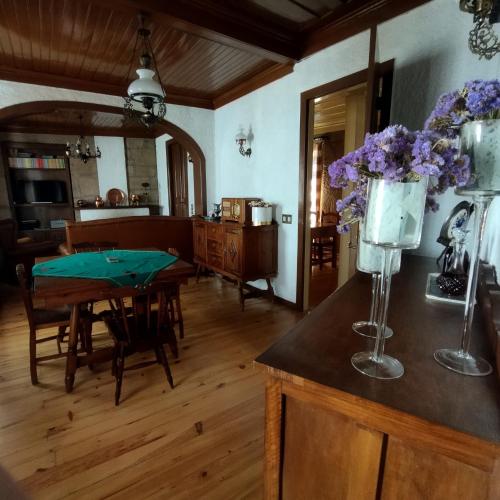 a living room with a table with a vase of purple flowers at Casa d`Avó Ná in Termas de Sao Pedro do Sul