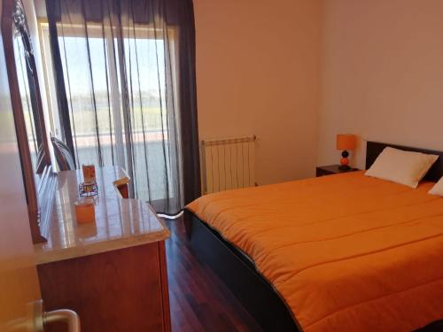 a bedroom with a orange bed and a window at CASA VISTA RIO ESPOSENDE in Esposende