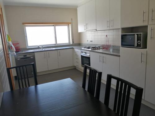 a kitchen with white cabinets and a table with chairs at CASA VISTA RIO ESPOSENDE in Esposende
