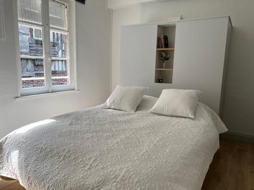 een witte slaapkamer met een bed met 2 kussens bij L'évasion in Honfleur