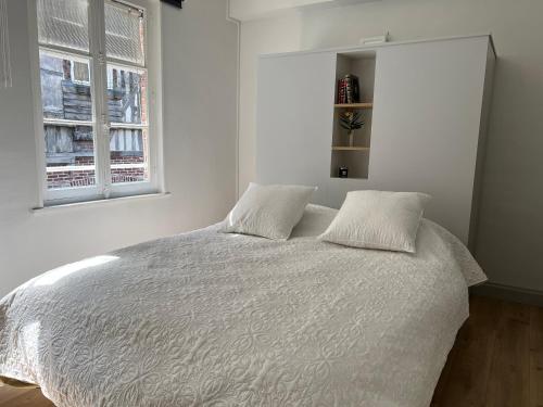- une chambre blanche avec un lit et deux oreillers dans l'établissement L'évasion, à Honfleur