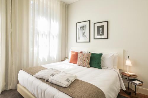 a bedroom with a large white bed with colorful pillows at Porto River Infante in Porto