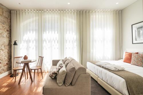 a bedroom with a large bed with a couch and a table at Porto River Infante in Porto