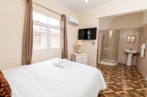 ein Schlafzimmer mit einem weißen Bett und einer Dusche in der Unterkunft Mariner Suites in Christchurch