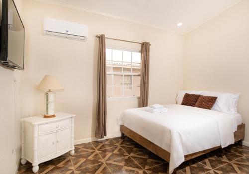 a white bedroom with a bed and a window at Mariner Suites in Christ Church