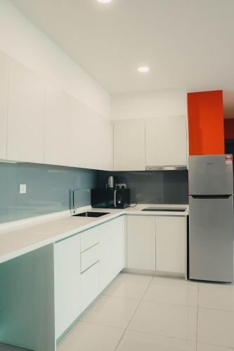 a kitchen with white cabinets and a refrigerator at Suasana Lifestyle Suites by Keystone in Johor Bahru