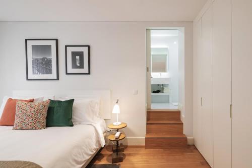 a white bedroom with a bed and a hallway at Porto River Infante in Porto