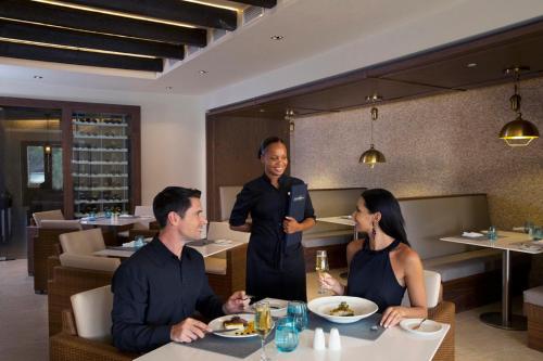 a man standing in a restaurant with three people at Royalton Hideaway Saint Lucia, An Autograph Collection All-Inclusive Resort - Adults Only in Gros Islet