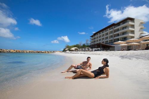 two people sitting on the beach in front of a hotel at Royalton Hideaway Saint Lucia, An Autograph Collection All-Inclusive Resort - Adults Only in Gros Islet