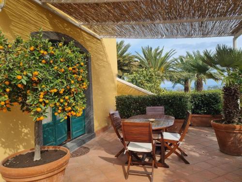 a patio with a table and chairs and an orange tree at Torre Archirafi Resort in Riposto
