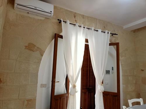 1 dormitorio con cortinas blancas y ventana en Case Vacanze Mariposa, en Favignana