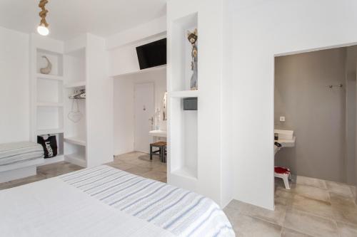 a white bedroom with a bed and a desk at Irini Rooms in Naousa