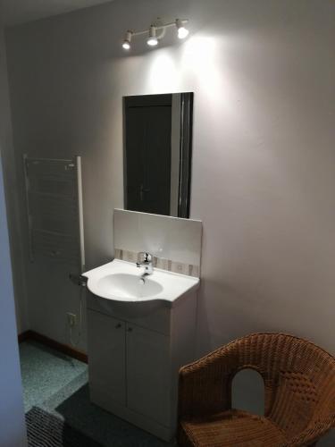 une salle de bain avec un lavabo, un miroir et une chaise dans l'établissement La maison d'André, à Taden