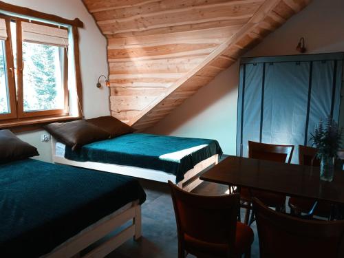 Habitación con 2 camas, mesa y ventana en Noclegi Kamionka en Cisna