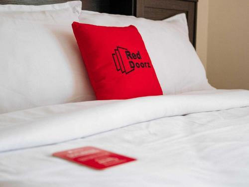 a red pillow sitting on top of a white bed at RedDoorz Plus @ Taman Madiun in Madiun