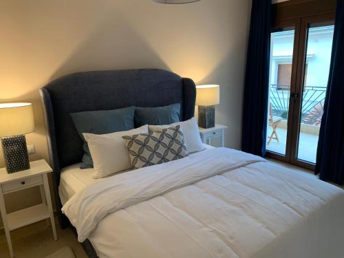 a bedroom with a bed with two lamps and a window at Divine Meteora Luxury midtown apartment in Kalabaka