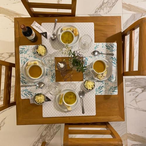 a table with cups and bowls of food on it at Pousada Alpes Azul in Campos do Jordão
