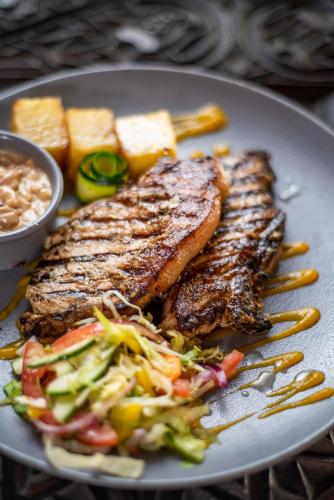 a plate with two pieces of meat and a salad at Safari Beach Hotel in Diani Beach