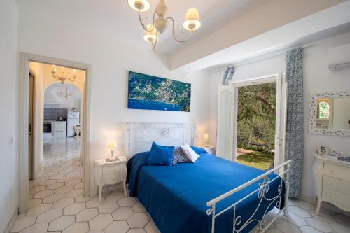 una camera con un letto blu e una finestra di YourHome - Relais Casa degli Angeli a Positano